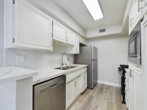 Apartments  for rent in Encino A modern kitchen featuring white cabinets, stainless steel appliances including a refrigerator, dishwasher, and built-in microwave, a double sink, and light wood flooring. White Oak Apartments in Encino 5465 White Oak Avenue Encino, CA 91316  P: 866-471-5691 TTY: 711 F: 818-647-0393